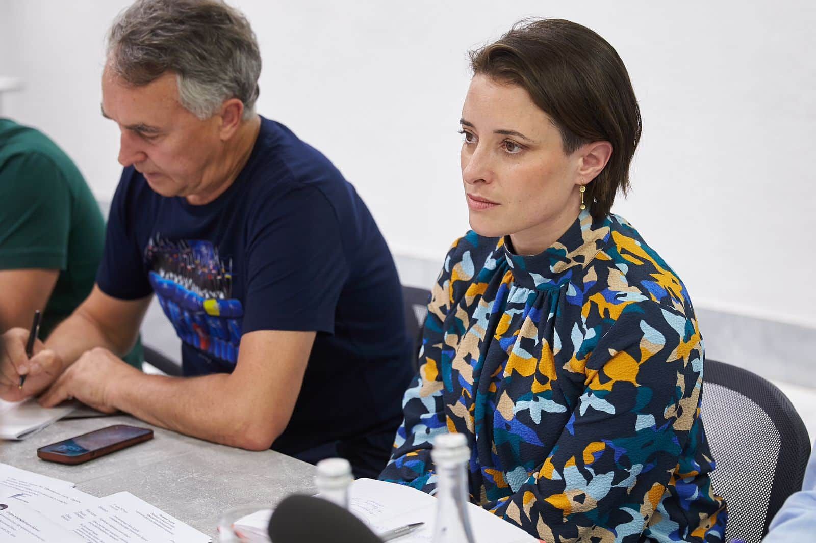 Visiting Ukraine, Karen Melchior speaking with Kharkiv mayor in a white room sitting at a table next to Petras