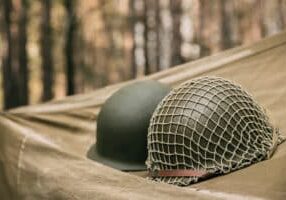 Metal Helmet Of United States Army Infantry Soldier At World War II. Helmet  On Camping Tent In Forest Camp.